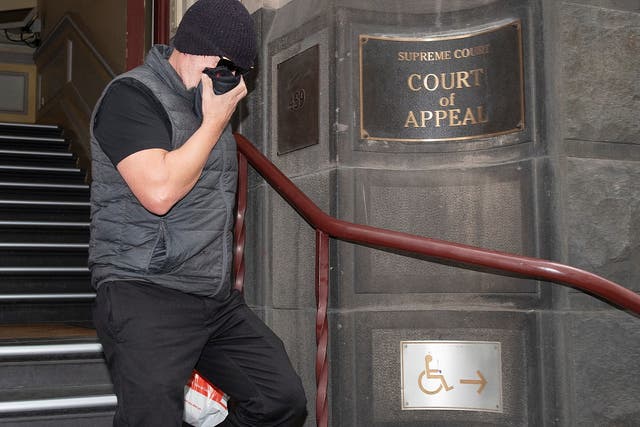 David Hingst, who brought the farting bullying claim, covers his face as he leaves the Court of Appeal in Melbourne