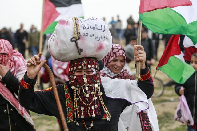 Palestinian women wave national flags during a demonstration marking the first anniversary of the ‘March of Return’ protests