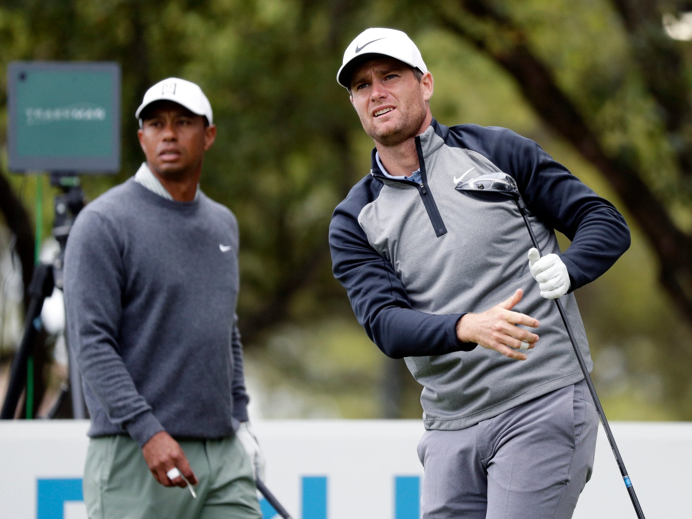 Lucas Bjerregaard, right, watches his drive on the eighth hole as Tiger Woods, left, looks on