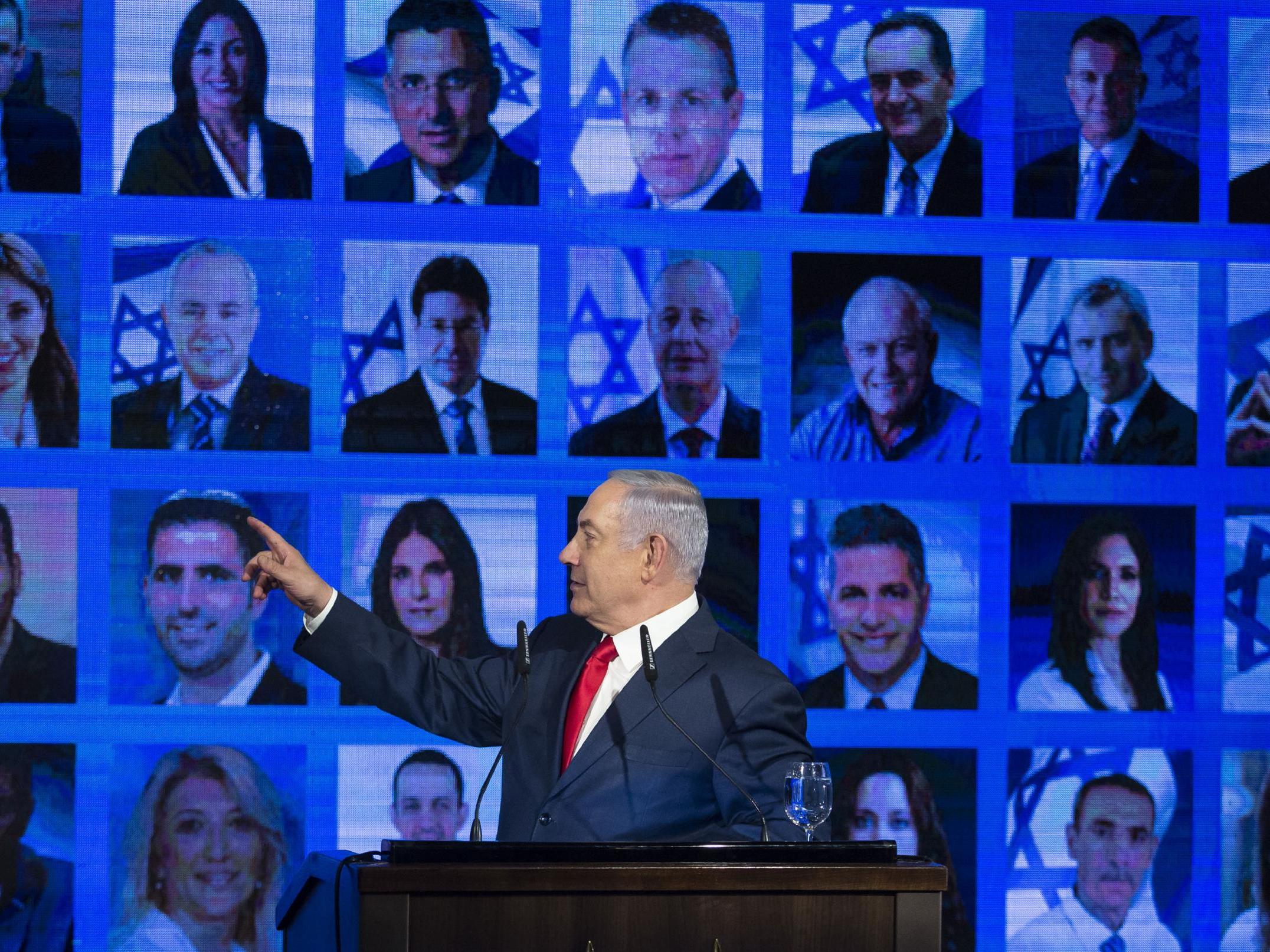 Benjamin Netanyahu points to photos of Likud party members as he delivers a speech during the launch of his party's election campaign on March 4, 2019