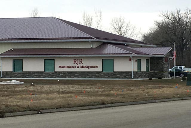 Cars are parked outside RJR Maintenance and Management in Mandan, N.D., on Monday, April 1, 2019. Police in North Dakota say "several" bodies have been found inside the business in suburban Bismarck.