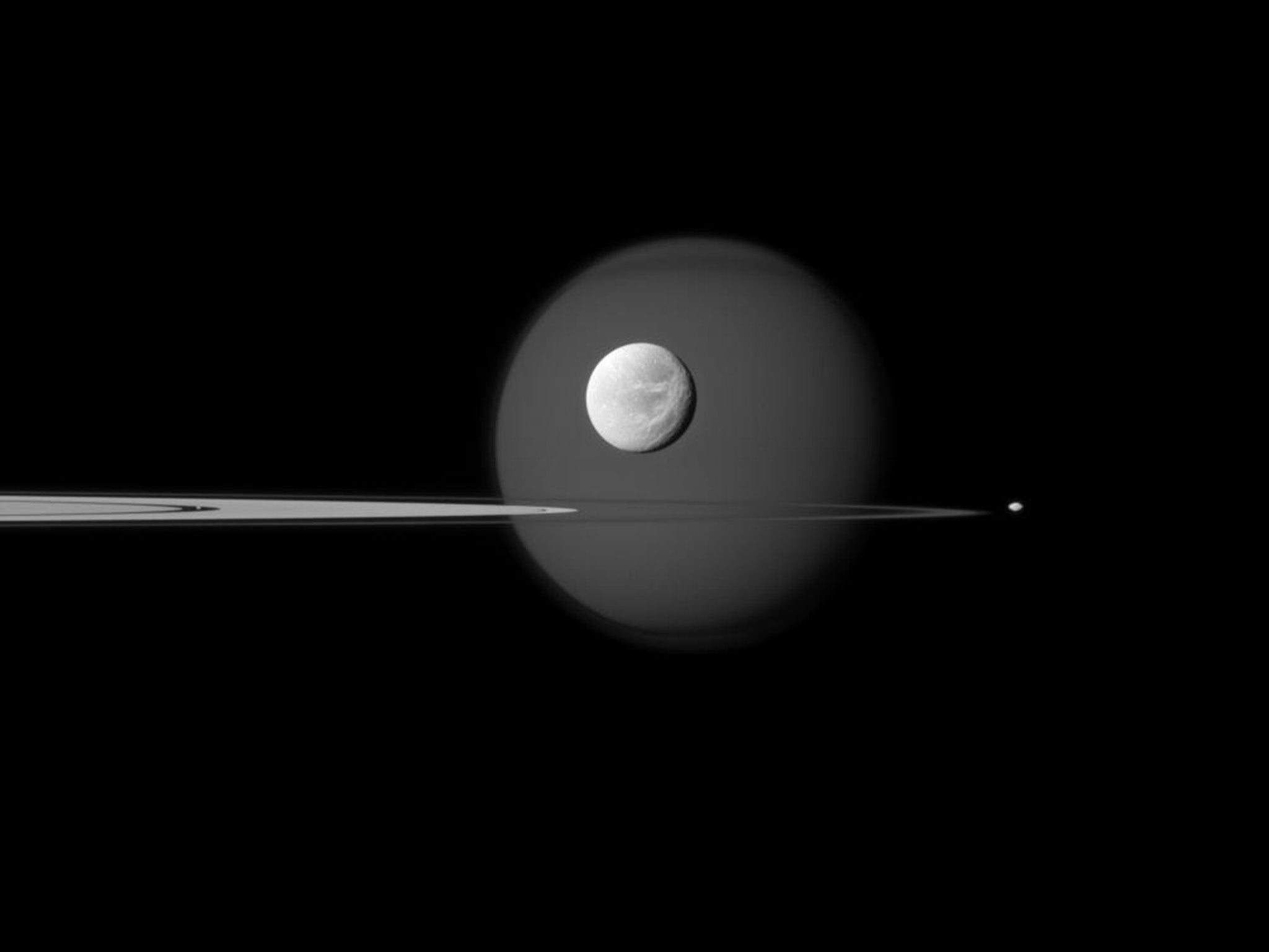 A quartet of Saturn’s moons surround and are embedded in the planet’s rings. Titan is the big moon in the background