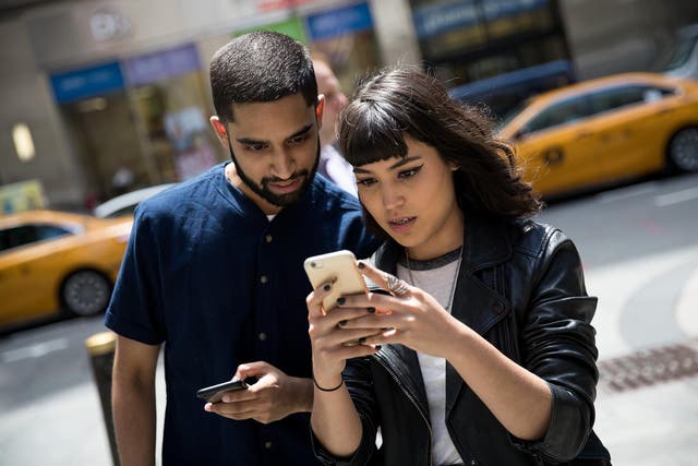 Sameer Uddin and Michelle Macias play Pokemon Go on their smartphones outside of Nintendo's flagship store, July 11, 2016 in New York City