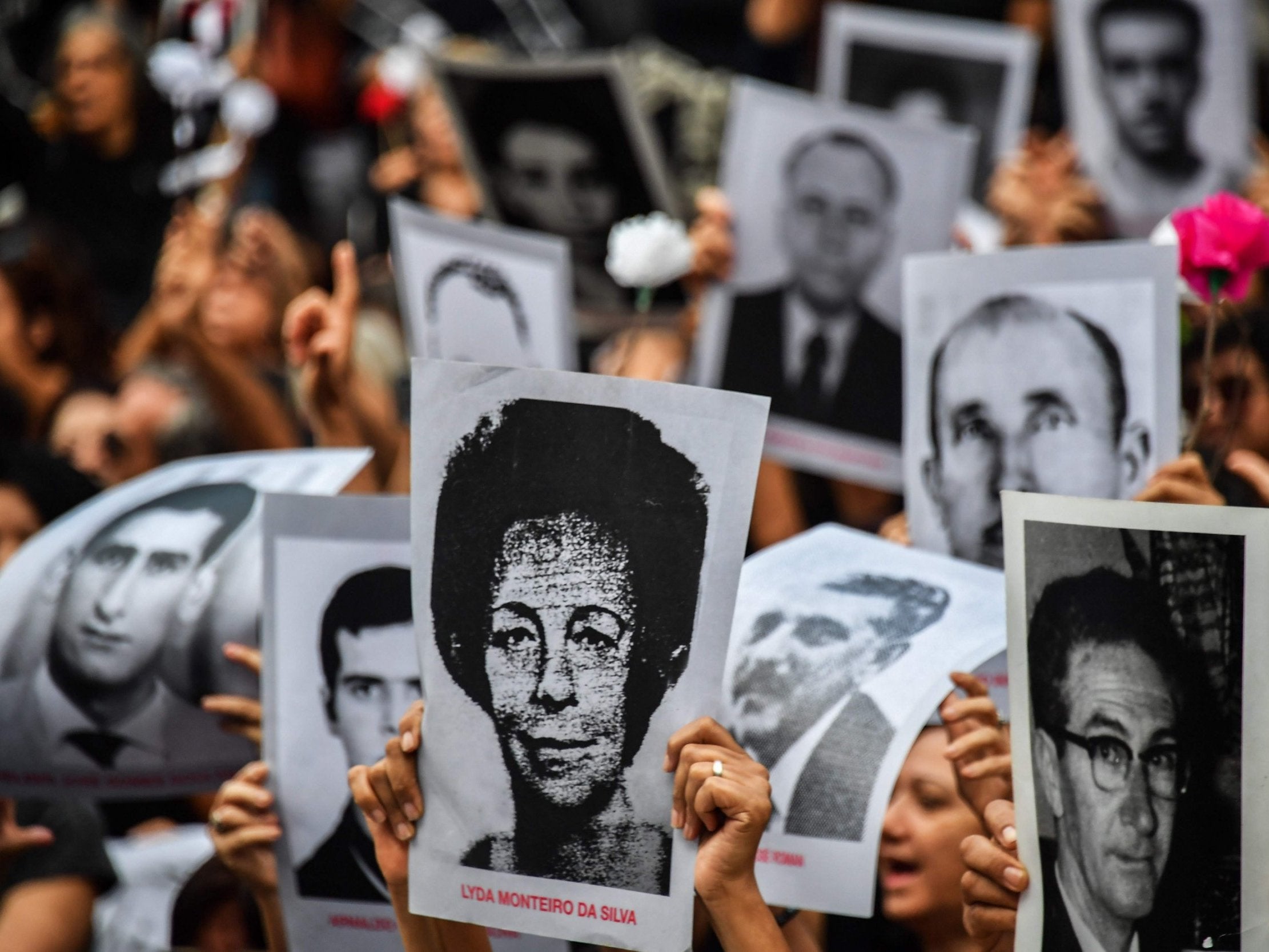 People hold pictures of those believed to have been killed or went missing during Brazil's 1964-1985 dictatorship, demonstrate on the 55th anniversary of the military coup.