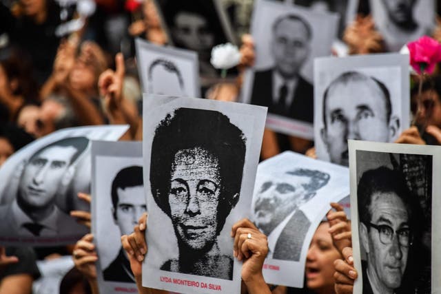 People hold pictures of those believed to have been killed or went missing during Brazil's 1964-1985 dictatorship, demonstrate on the 55th anniversary of the military coup.
