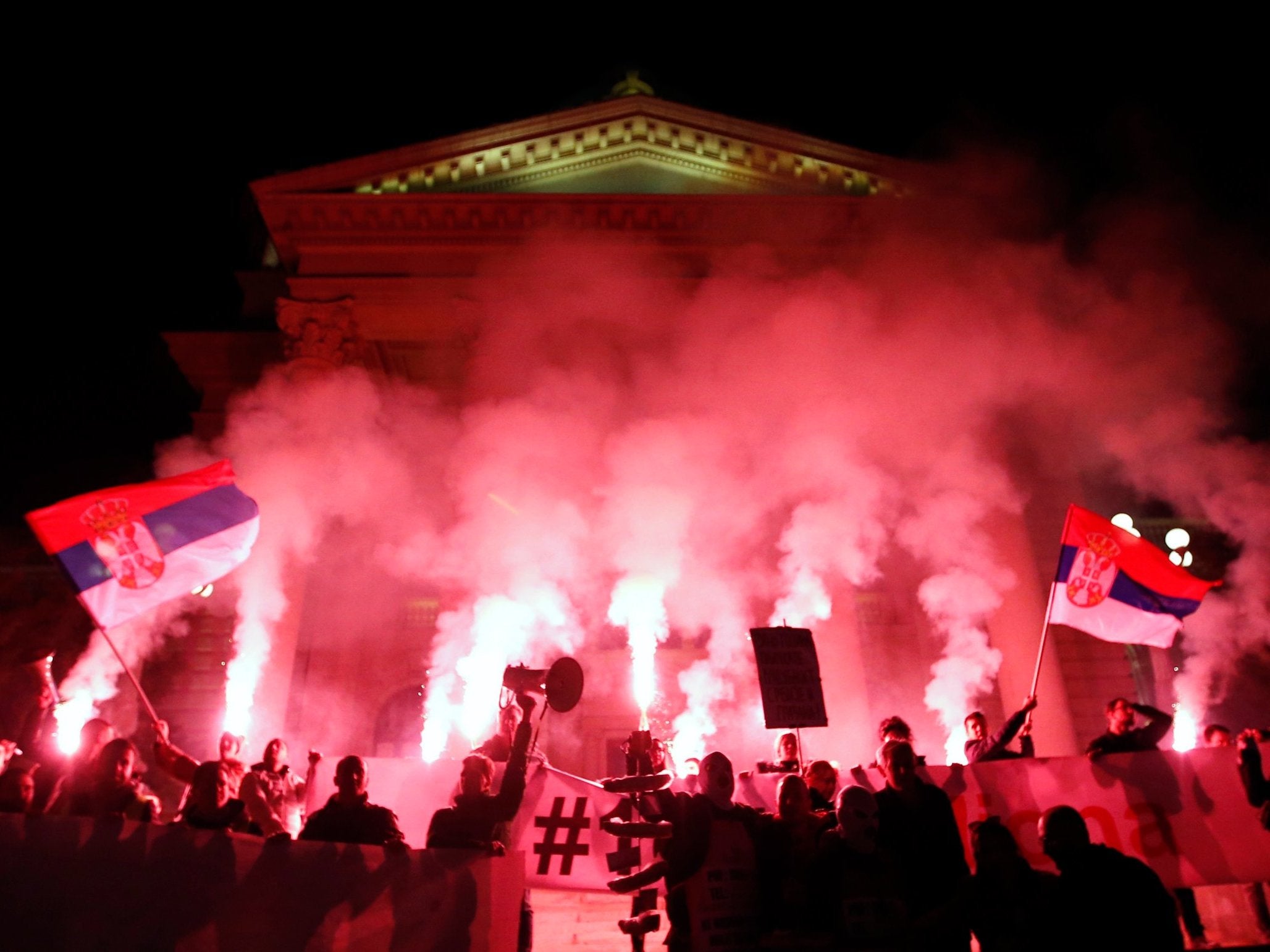 People light torches in front of the Serbian parliament building during a protest march against populist president Aleksandar Vucic