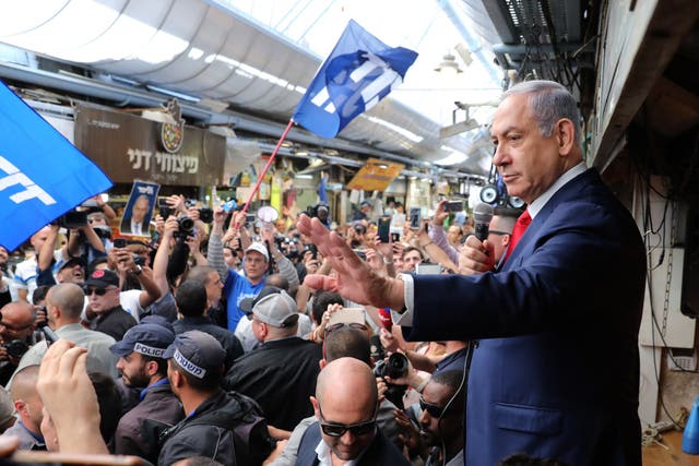Israeli prime minister Benjamin Netanyahu waves to supporters as he tours the Mahane Yehuda market with his wife during the final stage of his election campaign in Jerusalem, Israel
