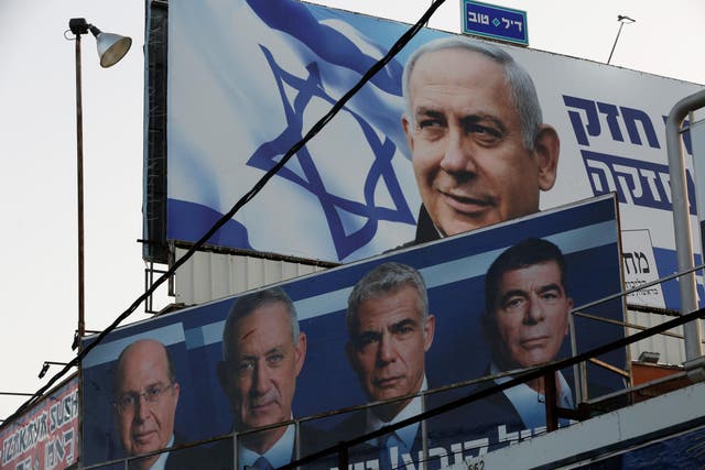 A Likud party election campaign billboard depicting Israeli Prime Minister Benjamin Netanyahu is seen behind a poster of Lt. Gen Gantz's Blue and White Party