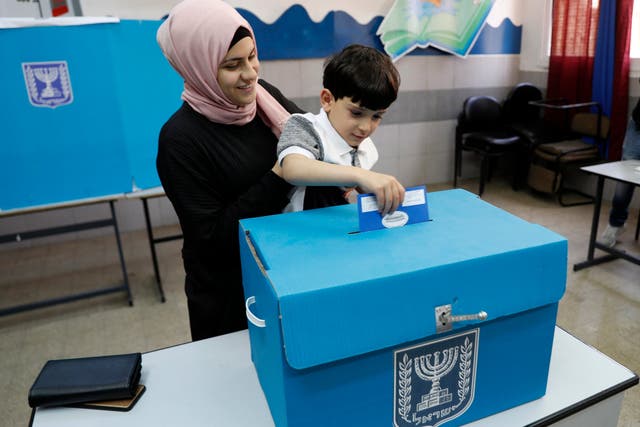 An Israeli Arab citizen from Taiybe town casts her ballot together with her son at a polling station