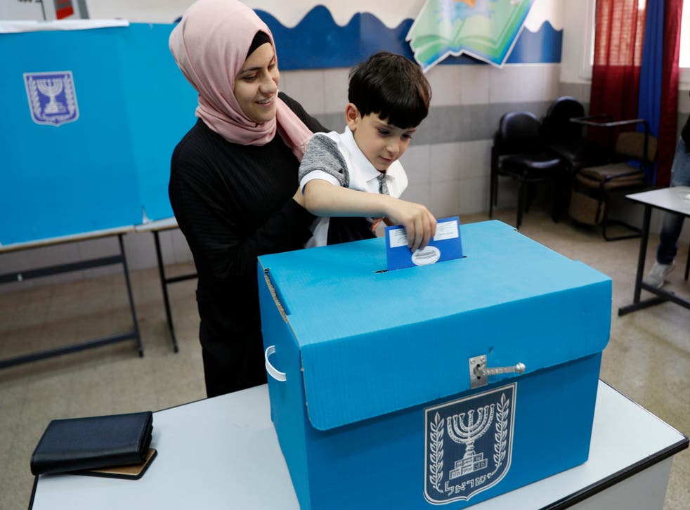 An Israeli Arab citizen from Taiybe town casts her ballot together with her son at a polling station