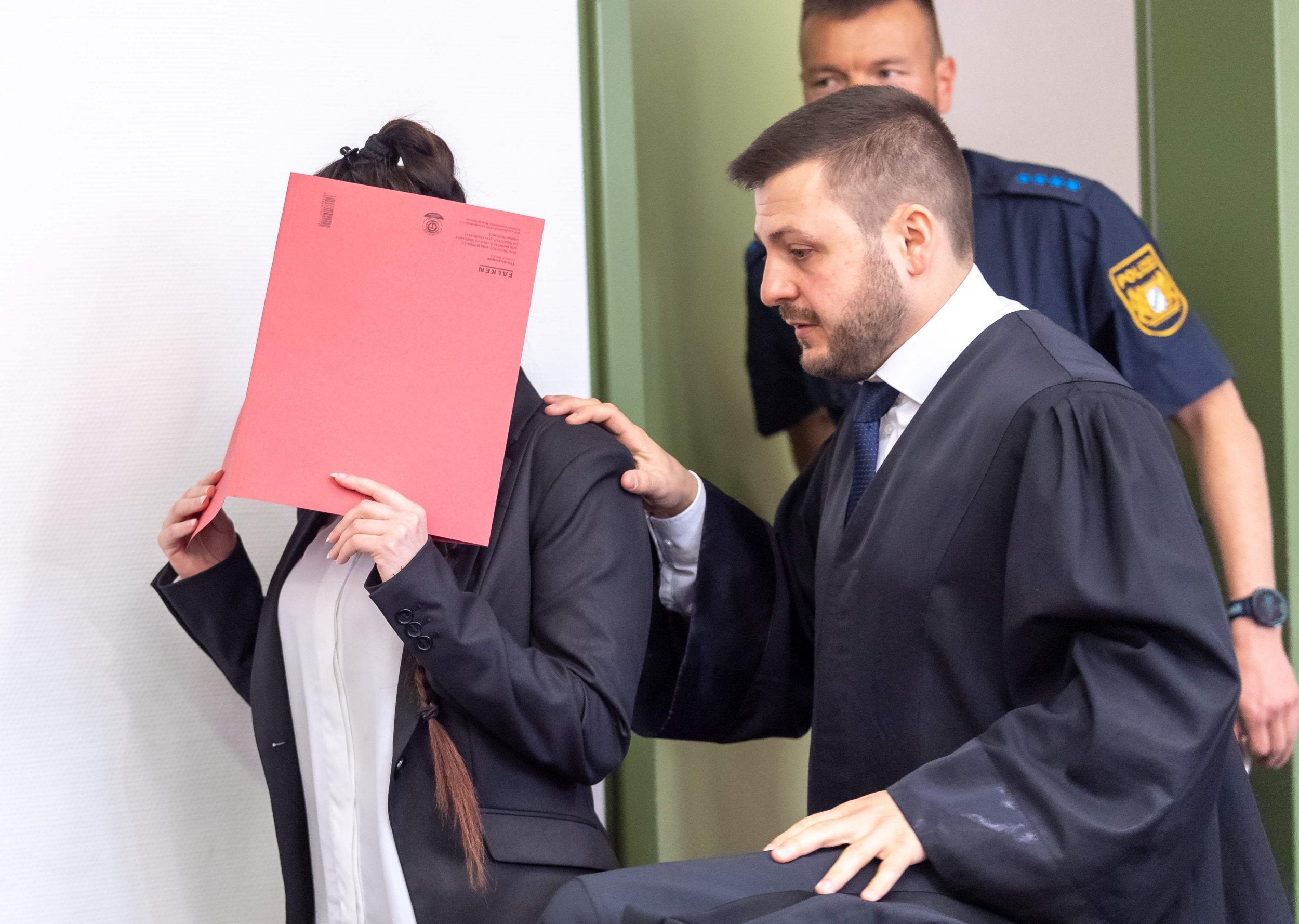 Defendant Jennifer W hides her face behind a folder and walks next to her lawyer Ali Aydin