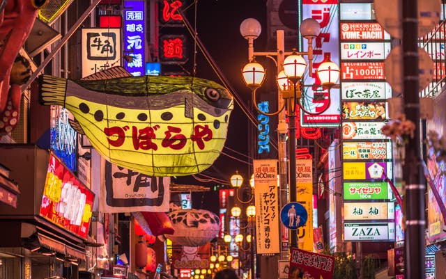 A neon pufferfish hangs above neon-lit Dotonbori in Osaka