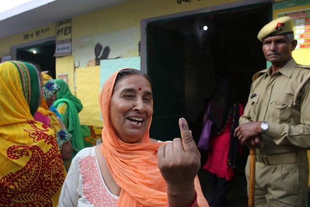 A woman shows the indelible ink mark on her index finger after casting her vote at a polling booth for the first phase of general elections