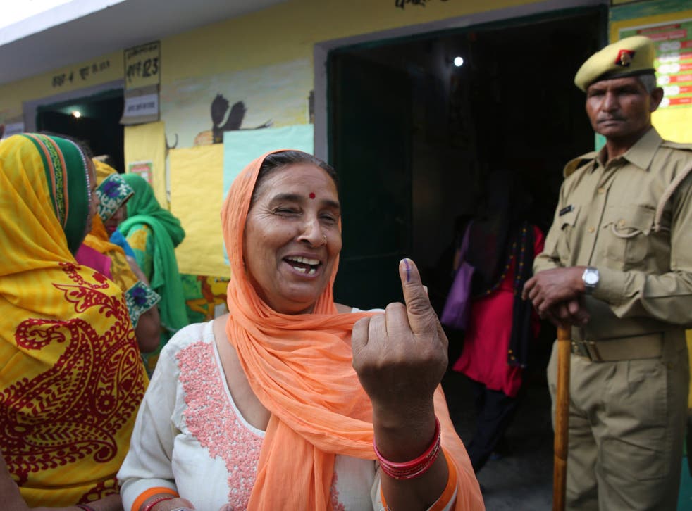 A woman shows the indelible ink mark on her index finger after casting her vote at a polling booth for the first phase of general elections