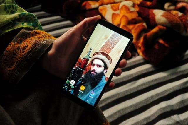 The sister of Owais Malik displays a picture of the suspected militant at her home in Kulgam, Kashmir