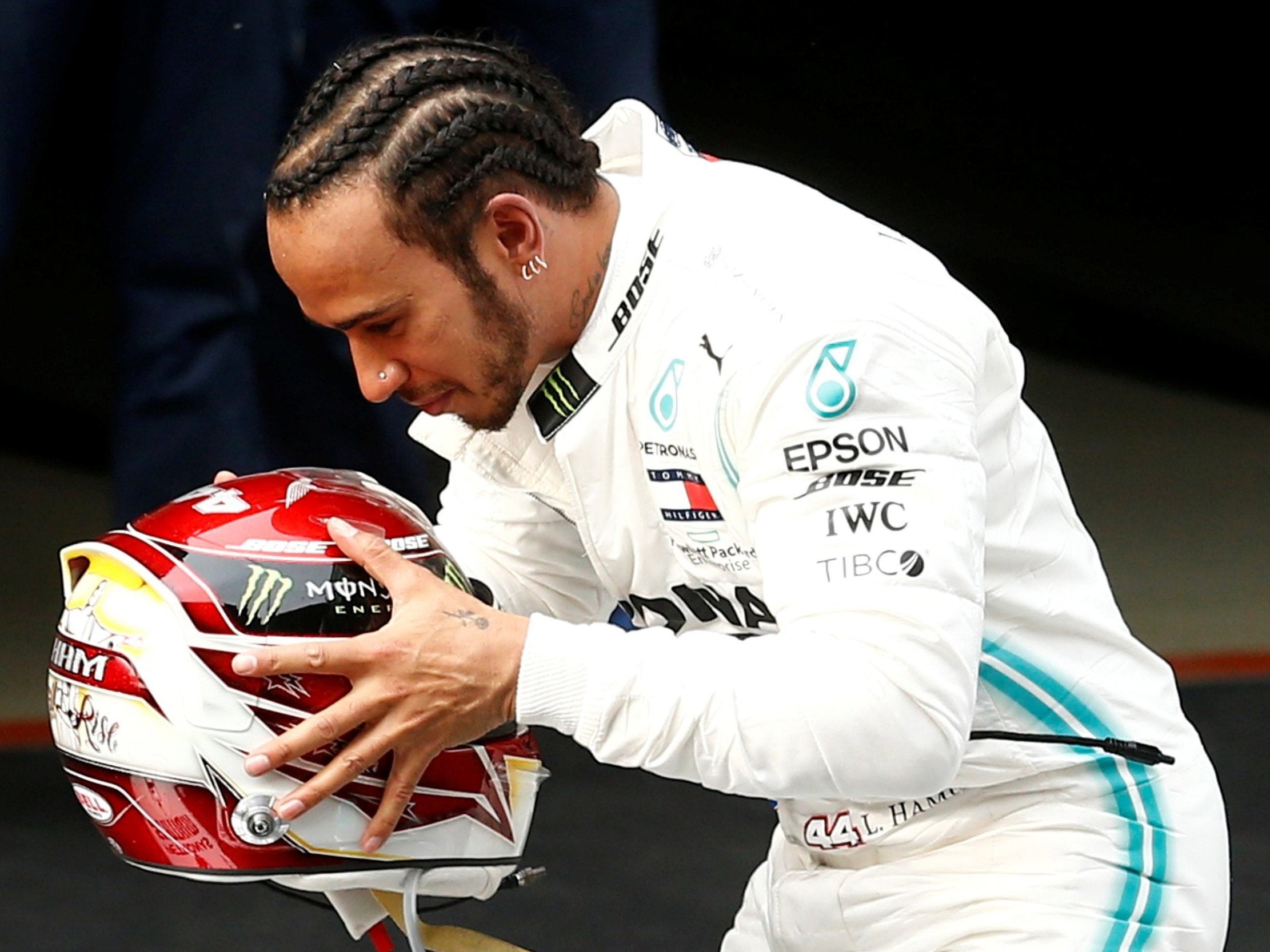 Hamilton kisses his helmet while standing atop his Mercedes