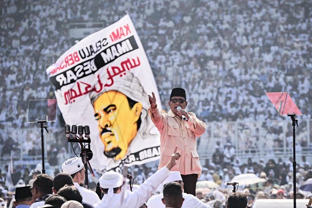 Prabowo Subianto addresses his supporters as someone waves banner of influential religious leader Habib Rizieq on 7 April