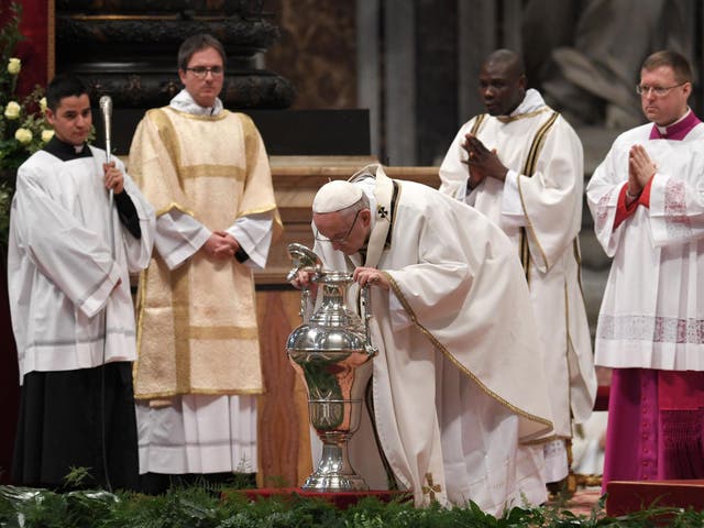 Pope Francis blows in an amphora containing holy oil during the Holy Chrism Mass on Maundy Thursday at St Peter's basilica in the Vatican on 29 March 2018