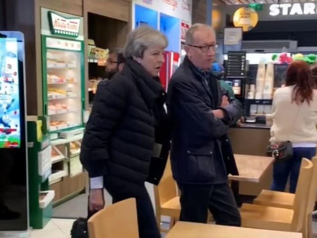 Theresa May and husband Philip May walk past the doughnut display at Shifnal services