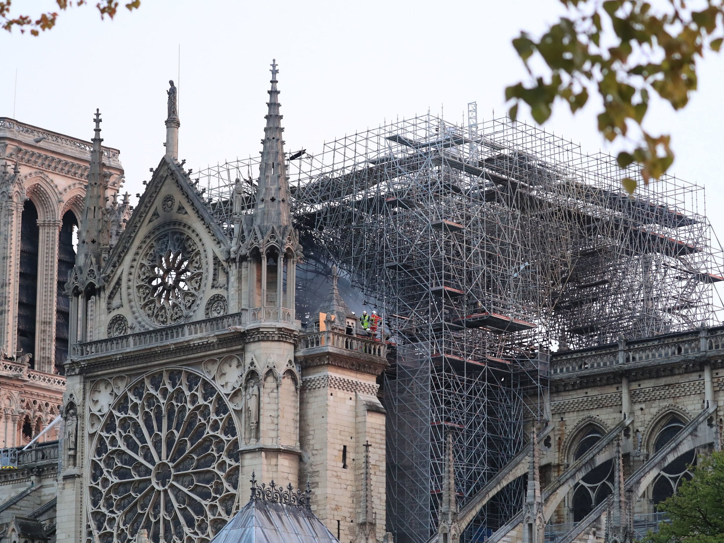 Firefighters assess the damage to the centre of the structure where, until yesterday afternoon, the cathedral's main spire stood