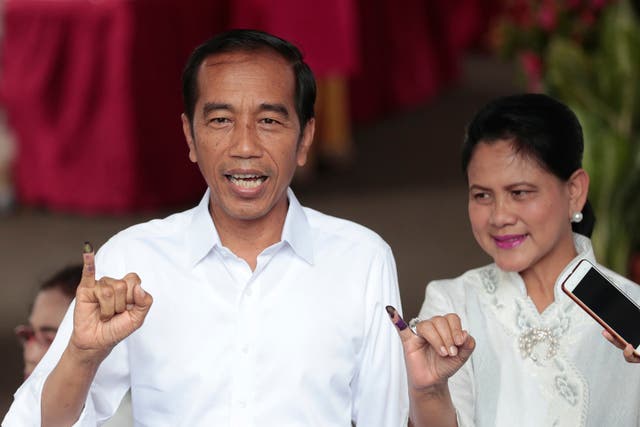 Indonesian president Joko 'Jokowi' Widodo and wife Iriana show their inked fingers after casting their ballots in the 2019 election