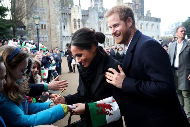 Prince Harry and Meghan Markle sign autographs and shake hands with children as they arrive to a walkabout at Cardiff Castle on January 18, 2018 in Cardiff, Wales