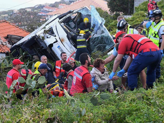 Firemen help victims after the tourist bus overturned near Funchal