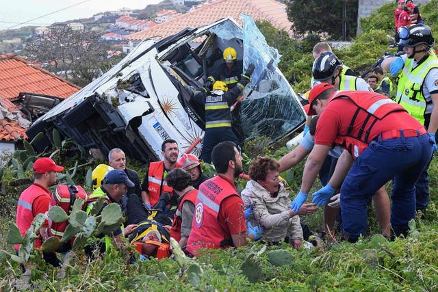 Firemen help victims after the tourist bus overturned near Funchal