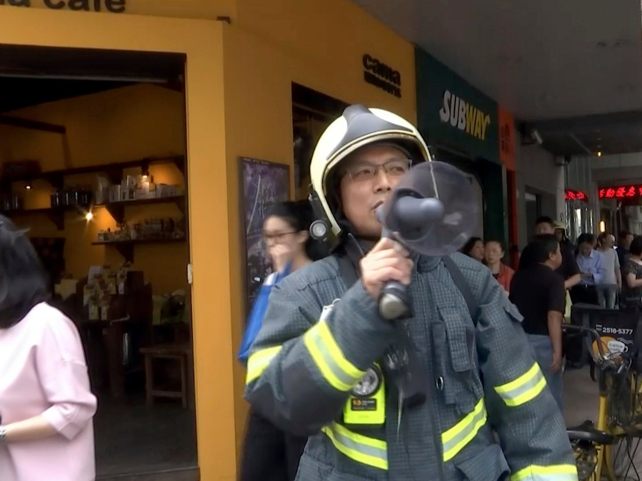 A firefighter evacuates people from a building in Taipei after earthquake