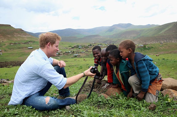 Prince Harry shows children a photograph he has taken on a visit to Lesotho