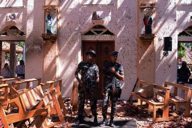 Sri Lankan military stand guard inside a church after an explosion in Negombo on 21 April