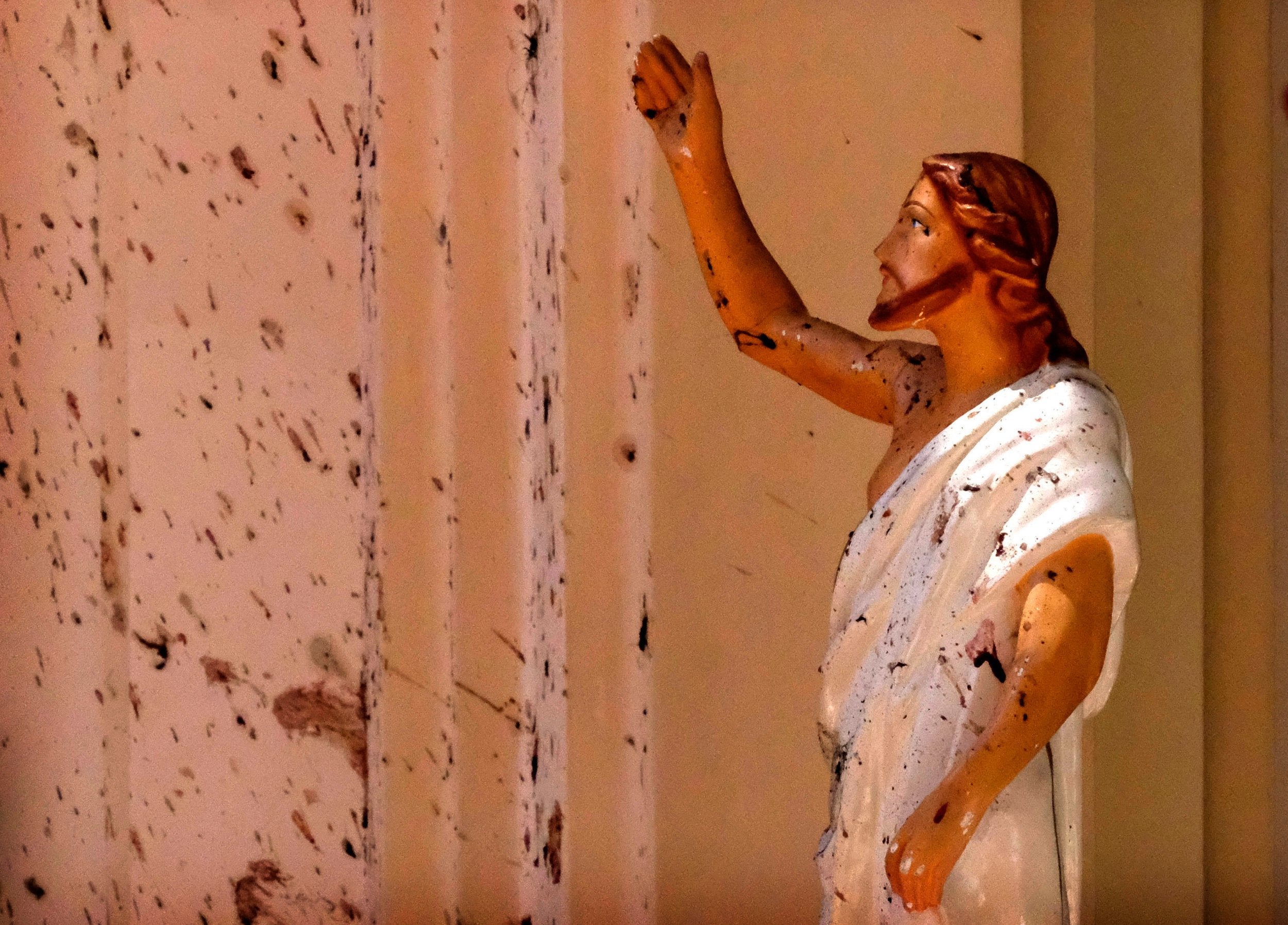 Blood stains are seen on the wall and on a Jesus Christ statue at the St Sebastian's Church after a blast in Negombo, north of Colombo, on Sunday