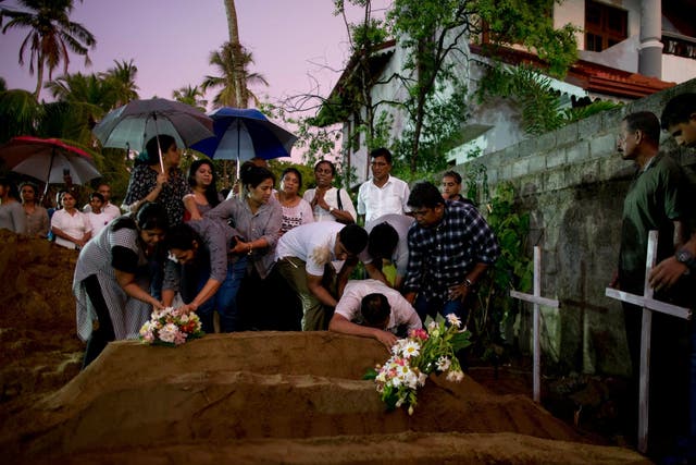 Relatives place flowers after the burial of three victims of the same family in Negombo on Monday