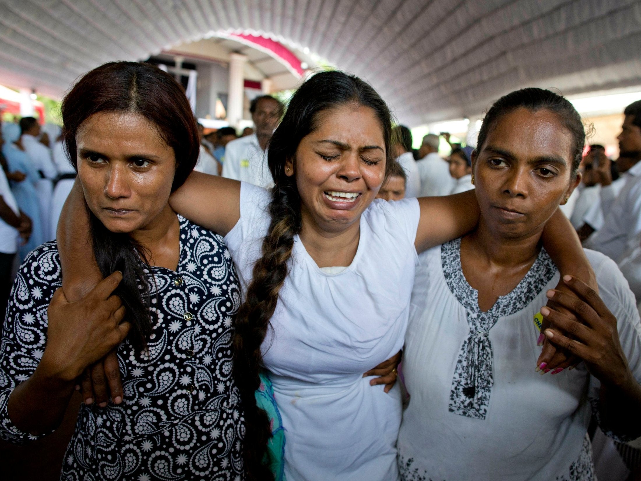 A grieving woman is supported during a funeral service attended by Cardinal Malcolm Ranjith for Easter Sunday bomb blast victims at St. Sebastian Church in Negombo, Sri Lanka, on Tuesday