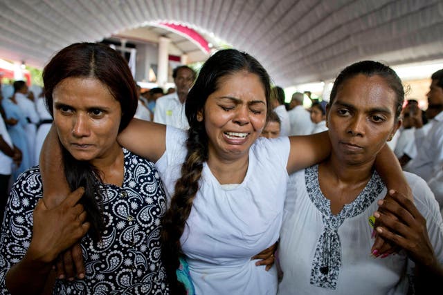 A grieving woman is supported during a funeral service attended by Cardinal Malcolm Ranjith for Easter Sunday bomb blast victims at St. Sebastian Church in Negombo, Sri Lanka, on Tuesday