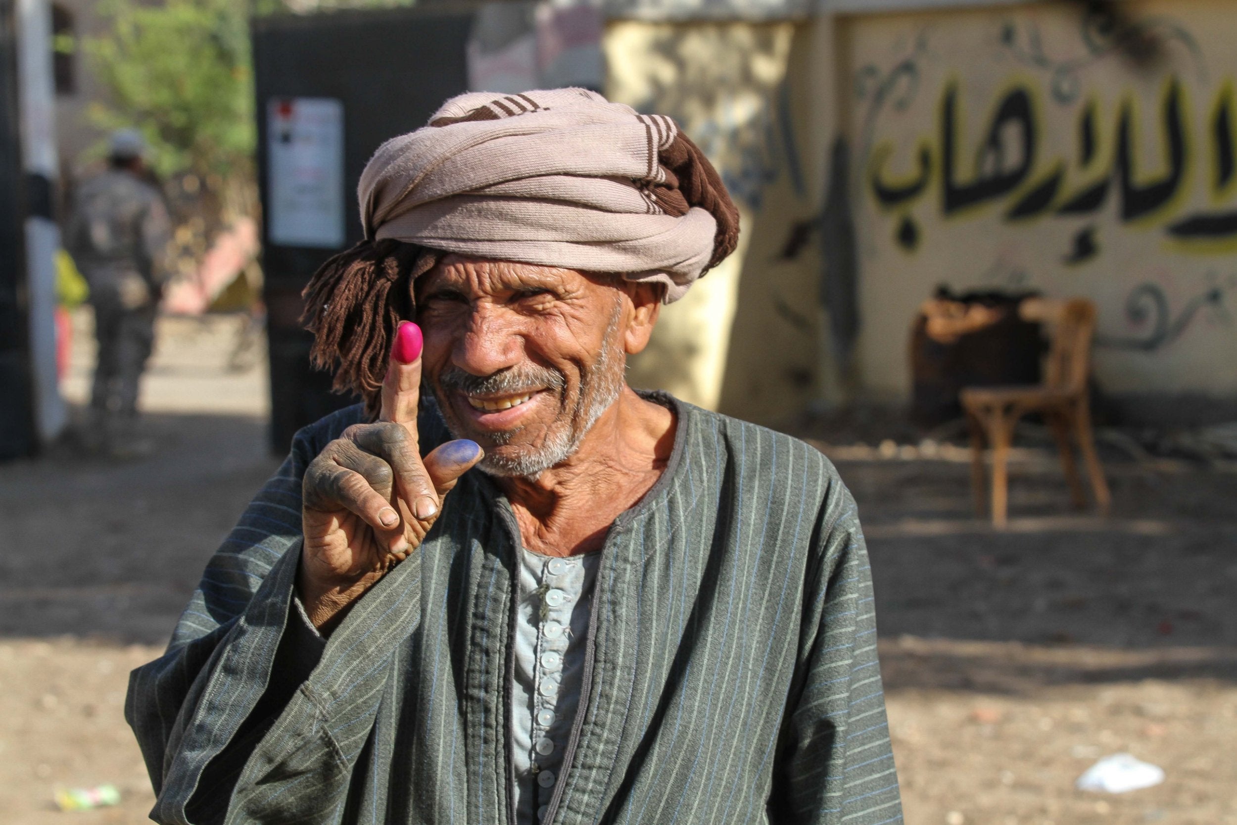 An Egyptian man flashes his ink-stained fingers after voting in a referendum on constitutional amendments, at a school in the village of al-Ayat, 90 km south of capital Cairo