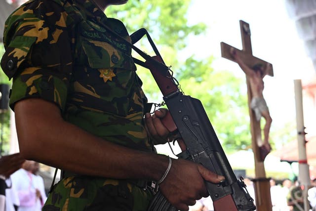 A soldier stands guard near a coffin of a bomb blast victim during a funeral service at St Sebastian's Church in Negombo