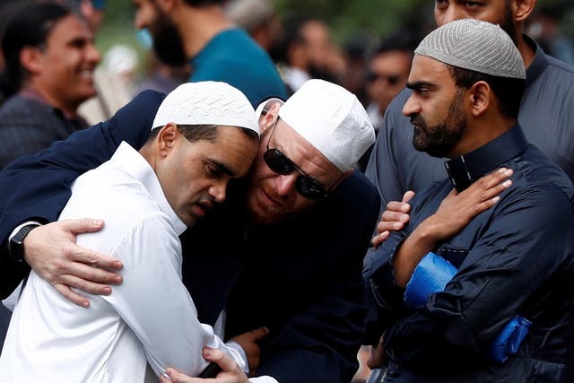 People comfort each other before the Friday prayers at Hagley Park outside Al-Noor mosque in Christchurch
