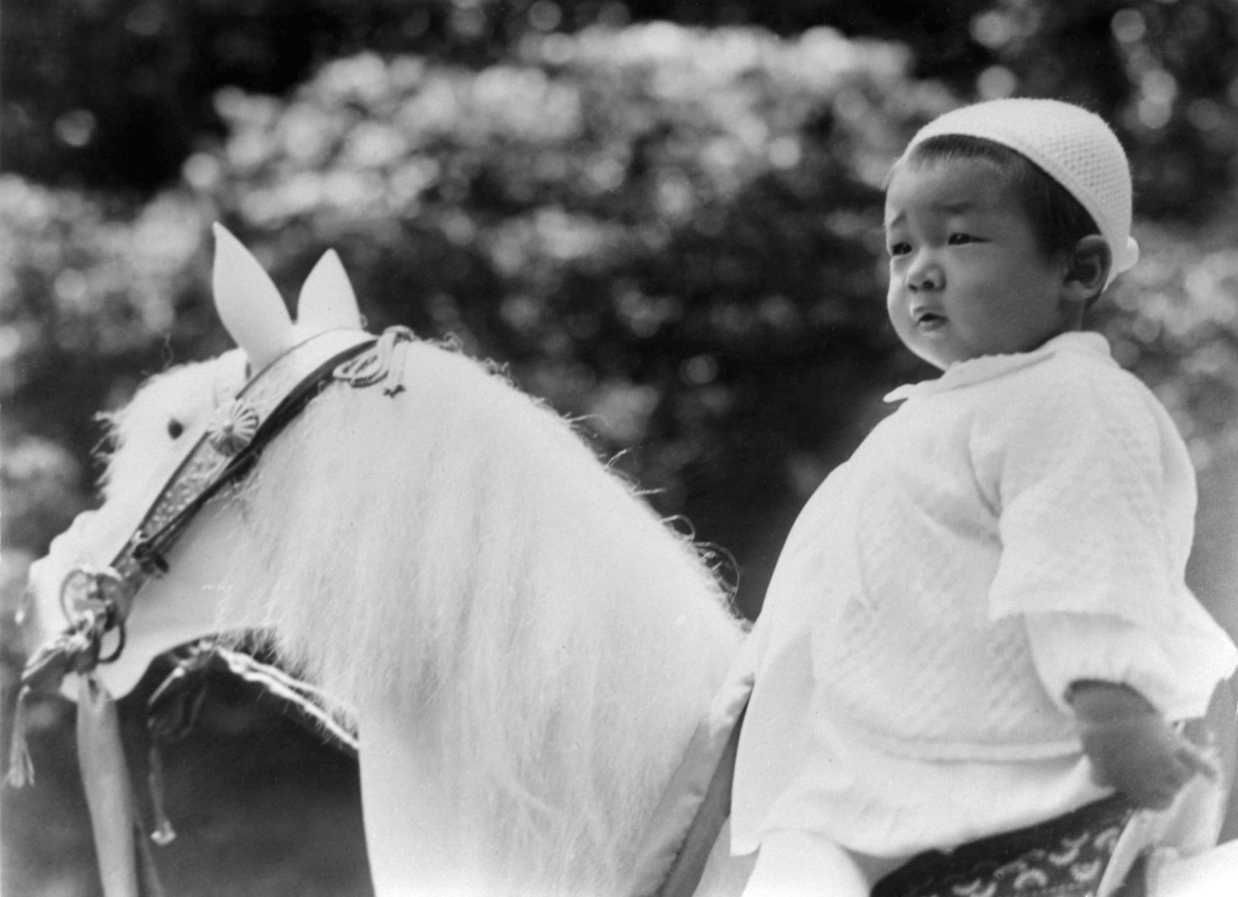 Baby Akihito sits on a rocking horse