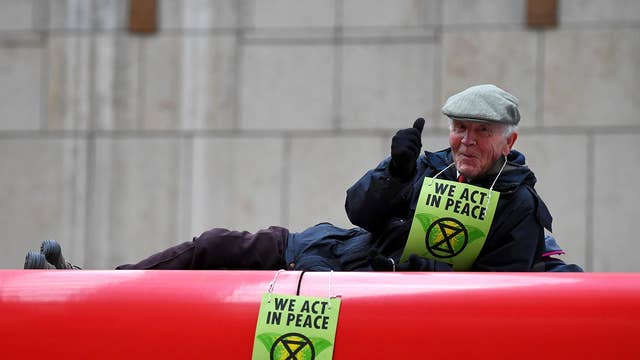 A protester gives a thumbs up as he stalls a DLR train at Canary Wharf station in London