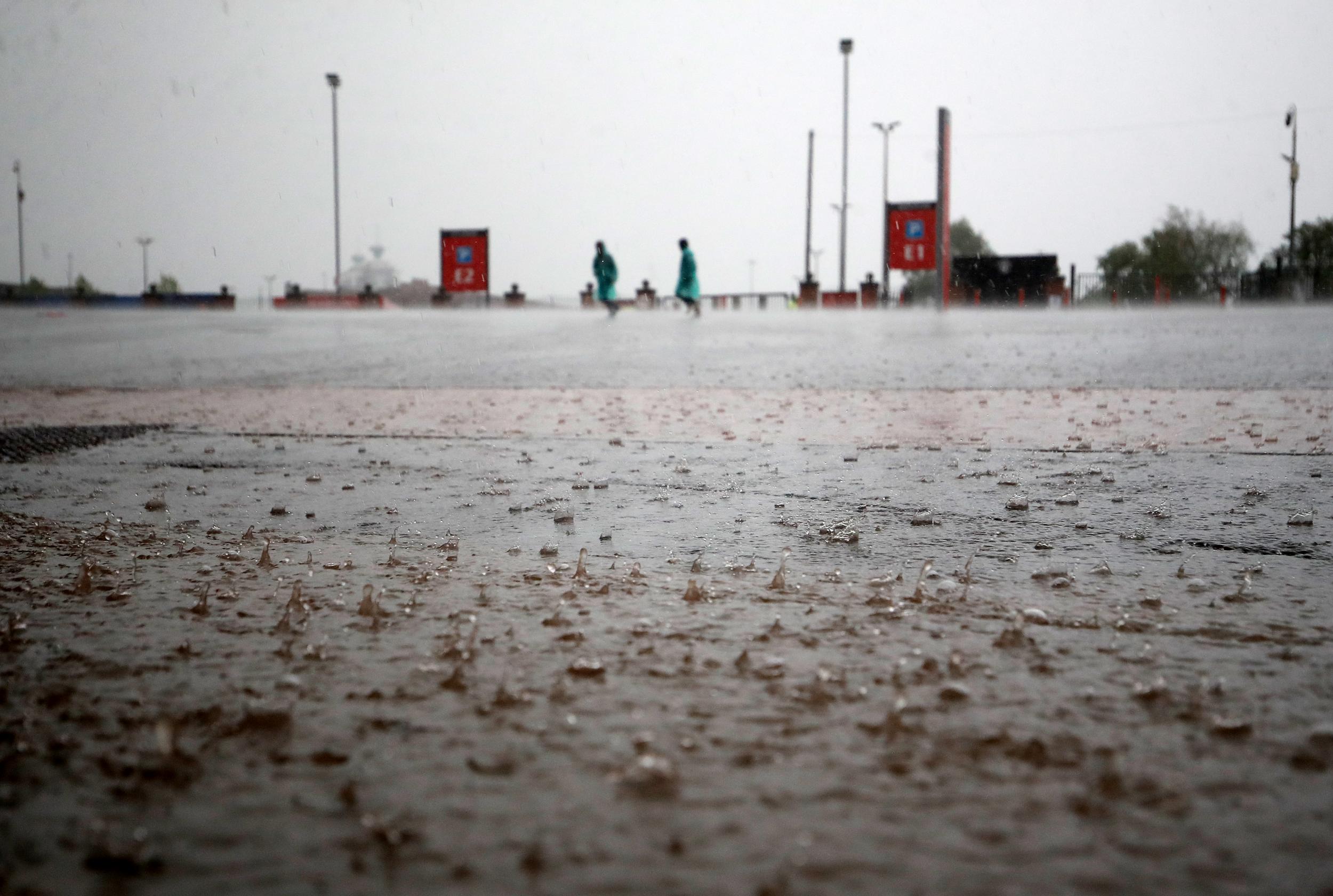 Fans race to the ground in the heavy rain before the Premier League match at Old Trafford, Manchester