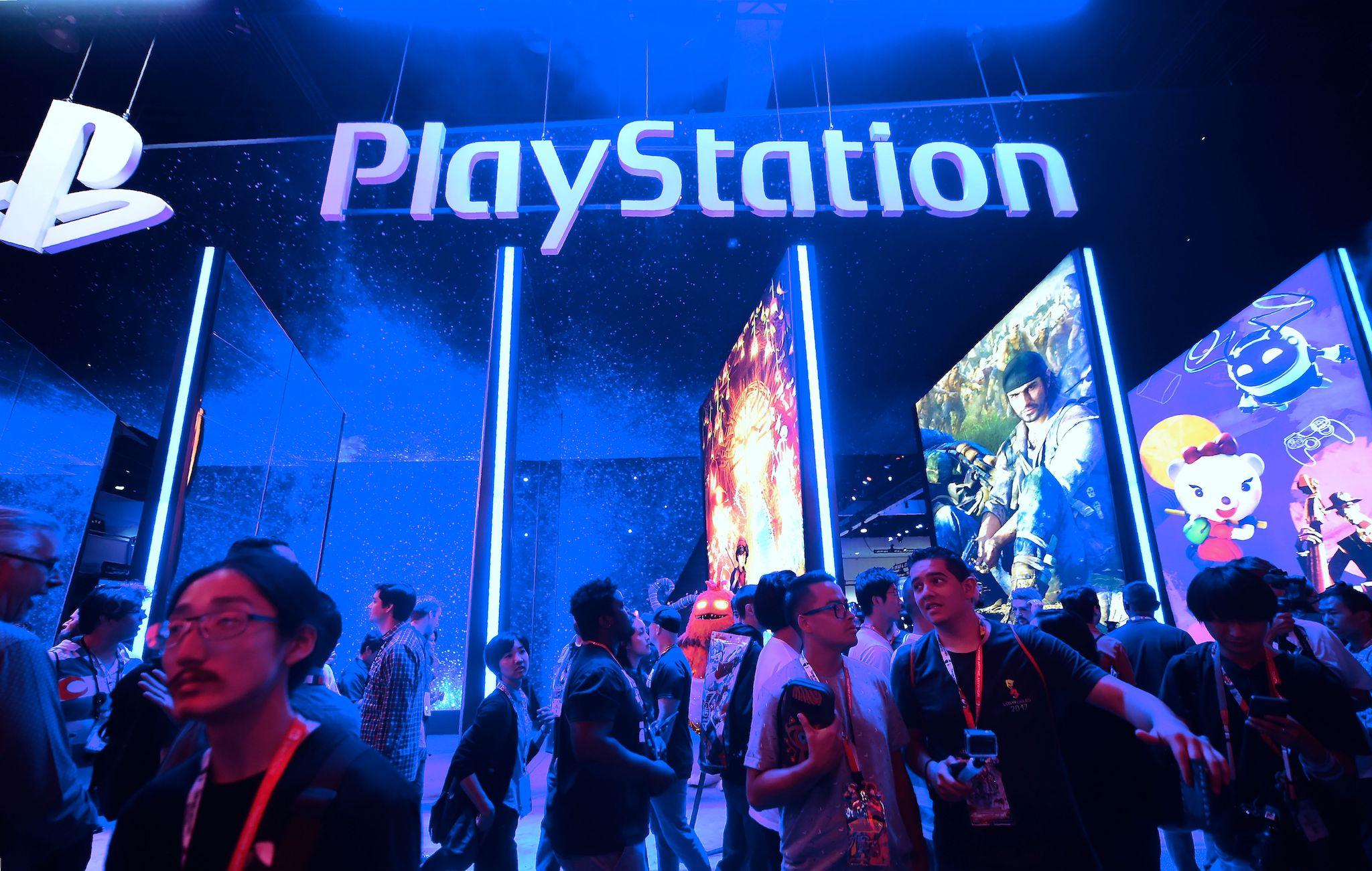 People wander in front of the Playstation posters at the 24th Electronic Expo, or E3 2018, in Los Angeles, California