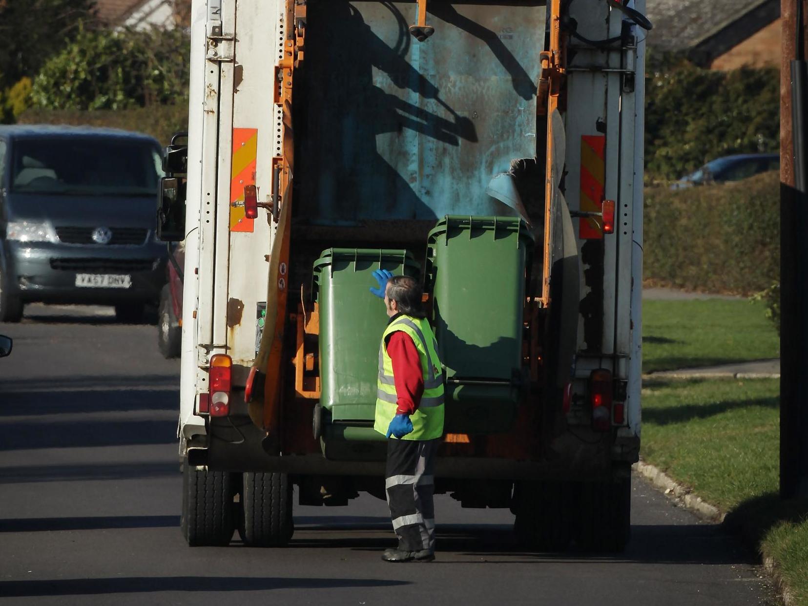 A refuse collector empties green 'wheelie' bins in March 2010
