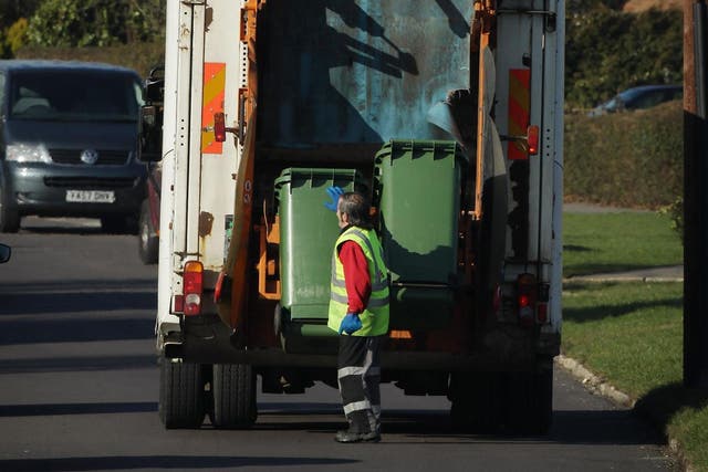 A refuse collector empties green 'wheelie' bins in March 2010