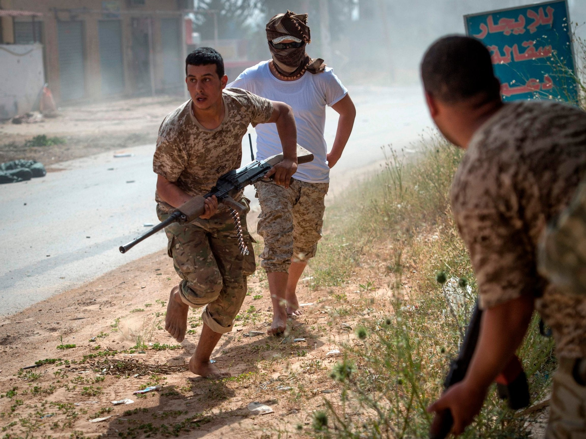 Fighters loyal to the government run for cover during clashes with forces loyal to Khalifa Haftar on 25 April (AFP/Getty Images)