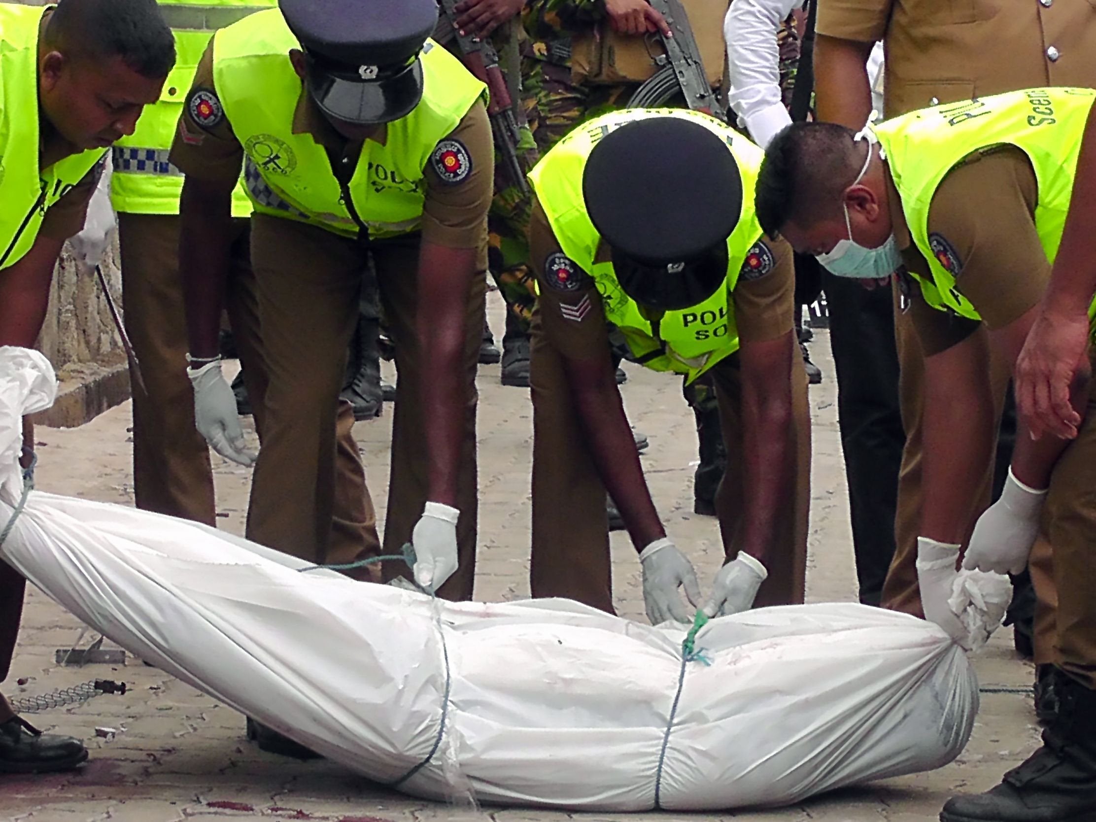 Policemen remove body from the site of battle between security forces and suicide bombers in Kalmunai