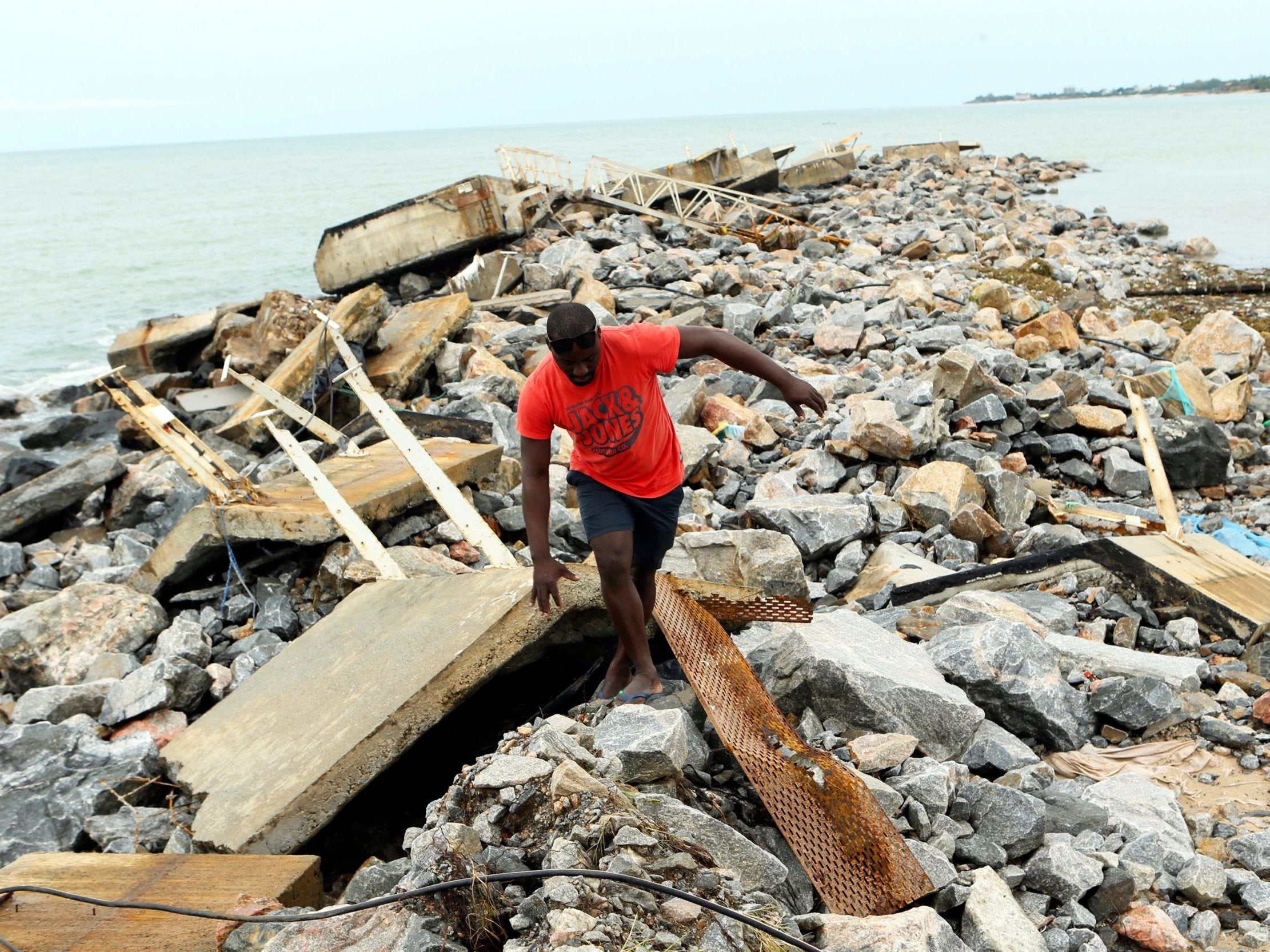 A man walks around a destroyed docking bay in Mozambique
