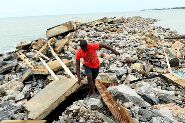 A man walks around a destroyed docking bay in Mozambique