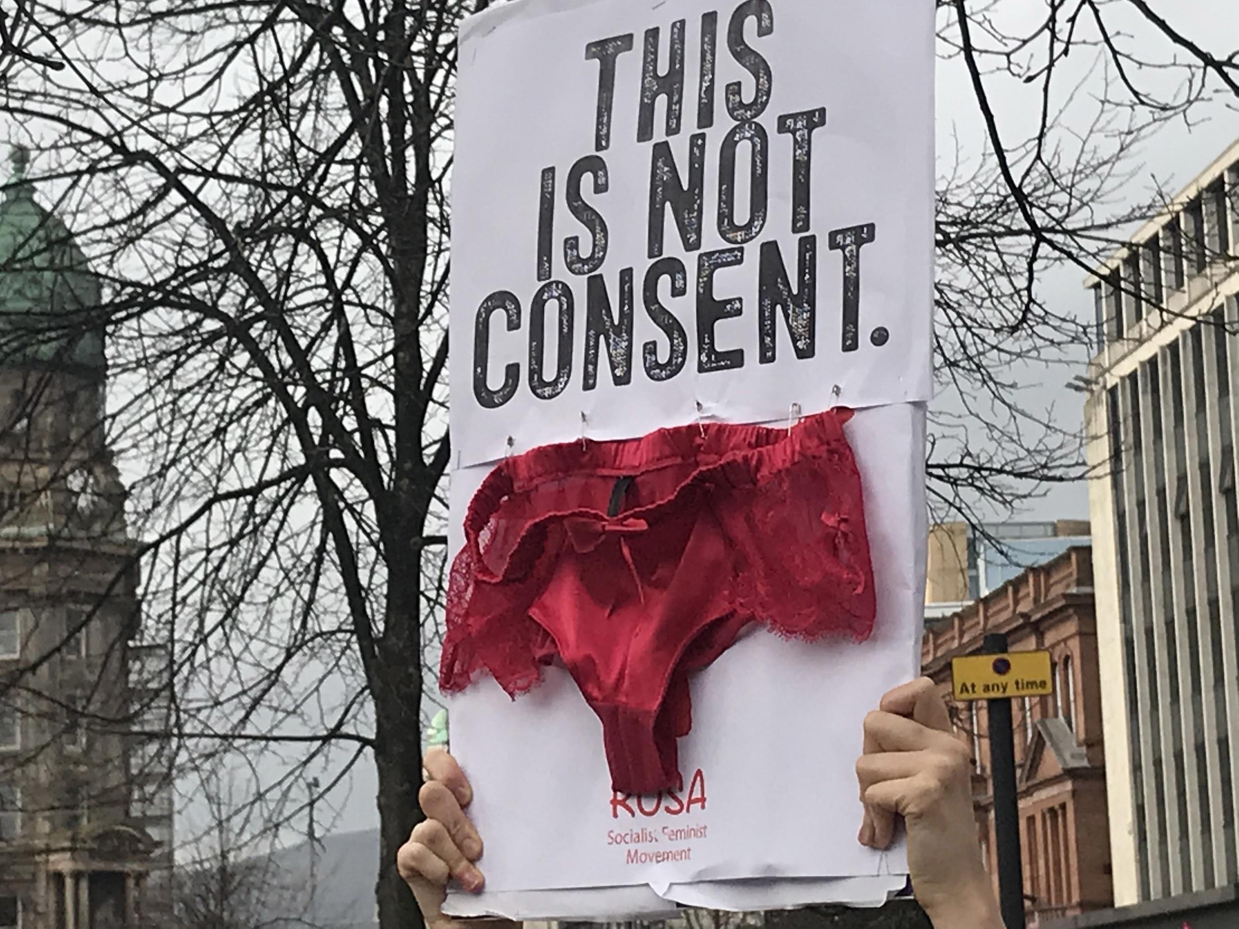 A protester at Belfast City Hall holds up underwear on a banner during a demonstration to highlight concerns over how rape trials are conducted.