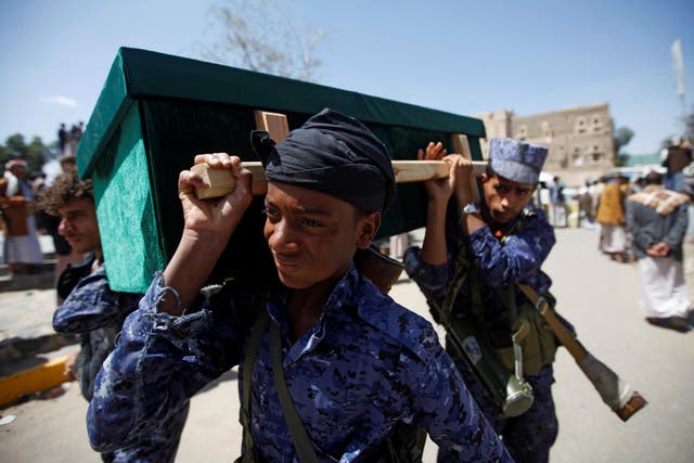 Houthi security officers carry a coffin during a funeral of people killed by a March air strike
